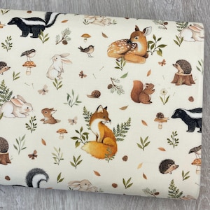 May include: Cream-colored fabric featuring a woodland animal print. The design includes illustrations of a fox, deer, skunk, rabbits, squirrels, birds, and mushrooms, along with leaves and butterflies. The fabric is suitable for various sewing projects.