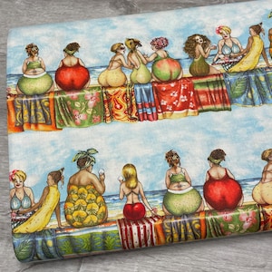 May include: Fabric featuring a whimsical beach scene with women in swimsuits sitting on colorful beach towels. The women have fruit-shaped bottoms. The background shows a blue sky and ocean.