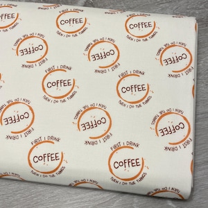 May include: Off-white fabric with a repeating pattern of coffee-themed text and graphics. Each design element includes the word "COFFEE" in a circular frame, along with the phrases "FIRST I DRINK" and "THEN I DO THE THINGS."