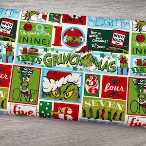 May include: Fabric with a repeating pattern featuring the Grinch, Christmas-themed text, and numbers. The design includes the Grinch in a Santa hat, gift boxes, and text like "Grinchmas" and "How the Grinch Stole Christmas!"