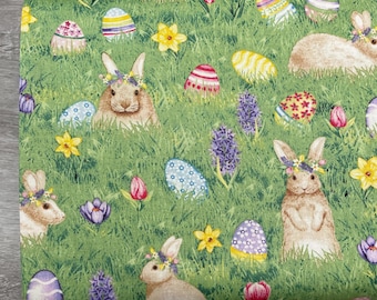 May include: Green fabric featuring an Easter theme. The design includes bunnies wearing floral crowns, colorful Easter eggs, yellow daffodils, purple hyacinths, and red tulips. The fabric has a grassy background.