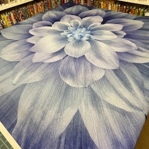 Peut inclure: Un grand tissu avec un motif floral détaillé. Le motif présente une vue rapprochée d'une fleur bleue et blanche, avec des pétales superposés rayonnant du centre. La palette de couleurs comprend des nuances de bleu et de blanc.