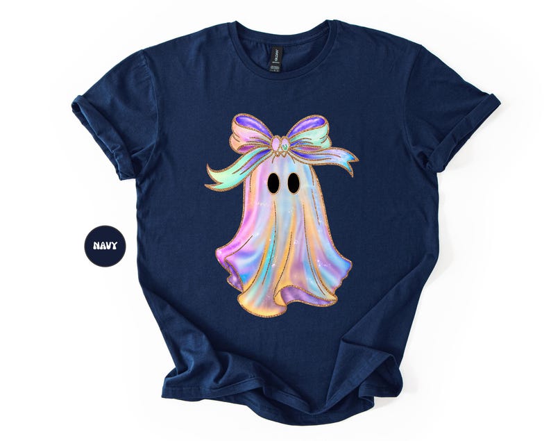 Op de afbeelding: Marineblauw t-shirt met een kleurrijk spookontwerp en een strik. De geest heeft een glinsterende, iriserende uitstraling met zwarte ogen. Het woord "NAVY" is gedrukt op een marineblauwe cirkel.