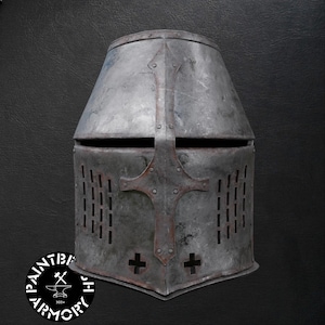 May include: A grey metal great helm featuring a flat top, a horizontal eye slit, and vertical ventilation slats on the sides. A central cross-shaped reinforcement plate is riveted to the front, with two small cross-shaped cutouts at the base.
