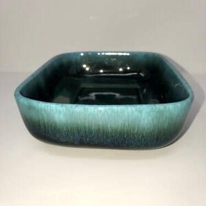 May include: A square ceramic dish with a teal glaze. The glaze has a mottled effect, with darker green and blue shades.