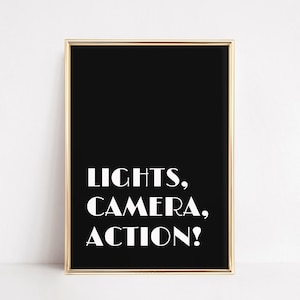 May include: Black and white printable wall art with a gold frame. The text reads "LIGHTS, CAMERA, ACTION!"
