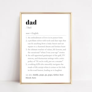 Puede incluir: Una definición imprimible de la palabra "dad" en blanco y negro sobre un fondo blanco. La definición incluye la pronunciación de la palabra, la parte de la oración y varias definiciones de la palabra. La definición está enmarcada en un marco dorado.