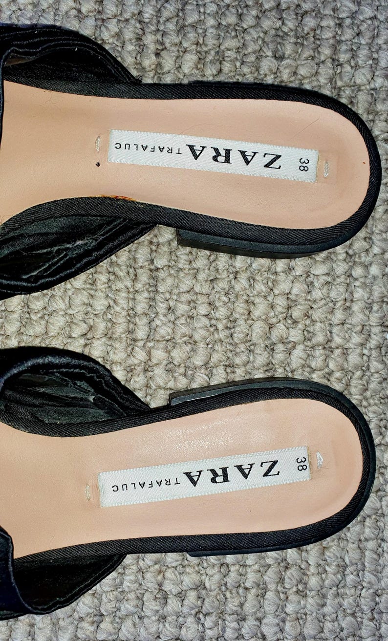 Puede incluir: Sandalias de tela negra con hebilla negra y una etiqueta blanca que dice "ZARA 38 TRAFALUC"
