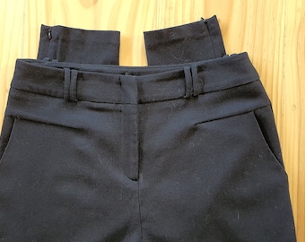 May include: Black pants with a zipper fly and belt loops. The pants have two front pockets and a back pocket.