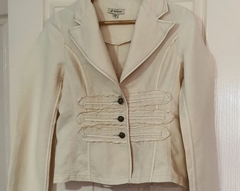 May include: A cream-colored blazer with a ruffled trim and four buttons down the front. The blazer has a collar and long sleeves.