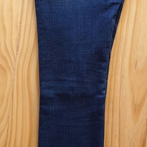 May include: A pair of dark blue denim jeans with a back pocket featuring a stitched-on True Religion logo.