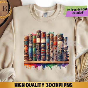 May include: Beige sweatshirt featuring a watercolor illustration of a stack of antique books on a wooden shelf. The books are in various colors with intricate designs. The bottom of the design has colorful paint drips. Text on the image reads "12 Free designs included" and "HIGH QUALITY 300DPI PNG".