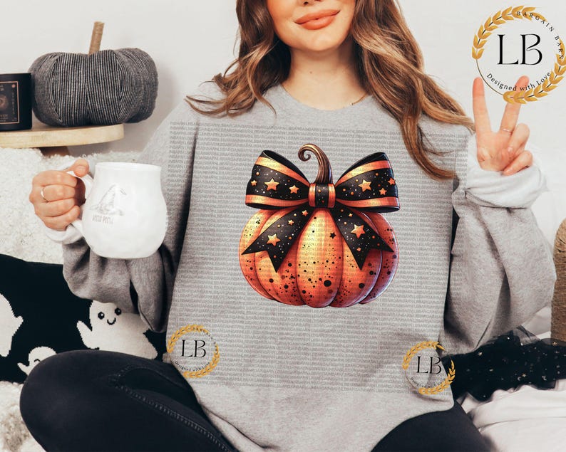 May include: A gray sweatshirt with a pumpkin design. The pumpkin is orange with black stars and a black and white bow. The bow has gold stars.