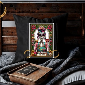 May include: A black throw pillow with a colorful illustration of a skeleton woman with a flower crown, holding a cup of coffee. The illustration is framed with a floral border and the text "The Mom" is at the bottom.