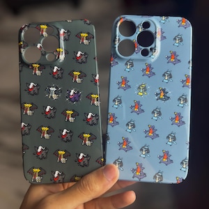 Op de afbeelding: Twee telefoonhoesjes met een herhalend cartoonkarakterpatroon. De ene hoes is donkergroen, de andere lichtblauw. Het cartoonkarakter heeft een rood, geel en zwart kleurenschema. De hoesjes hebben uitsparingen voor de camera en de knoppen van de telefoon.