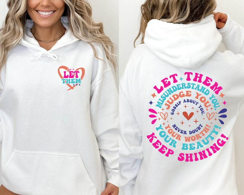 May include: White hoodie with a pink heart and the text "Let Them" on the front and a larger pink circle with the text "Let Them Misunderstand You. Judge You. Gossip About You. Never Doubt Your Worth! Keep Shining! Your Beauty!" on the back.