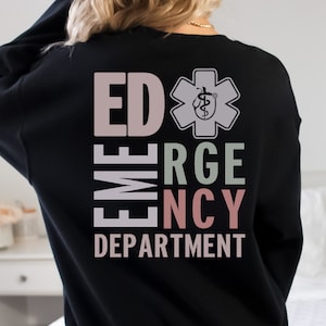 May include: Black sweatshirt with the text "ED EMERGENCY DEPARTMENT" in vertical columns with a star of life symbol in the center. The text is in different colors, including pink, light pink, and green.