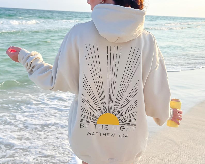 May include: A white hoodie with a black sunburst design and the text "BE THE LIGHT" and "MATTHEW 5:14" on the back.