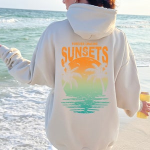May include: A cream colored hoodie with a graphic on the back that says "FOREVER CHASING SUNSETS" with a sunset and palm trees in a circle.