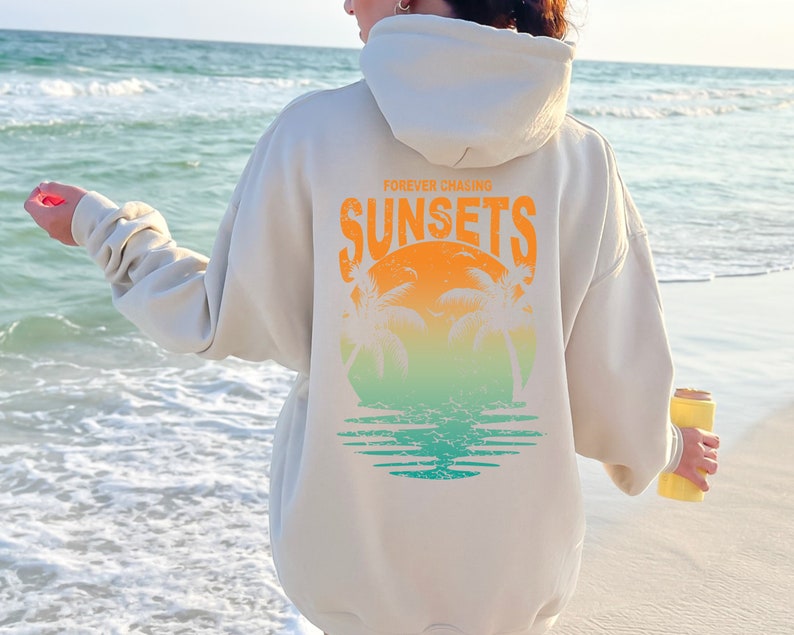 May include: A cream colored hoodie with a graphic on the back that says "FOREVER CHASING SUNSETS" with a sunset and palm trees in a circle.