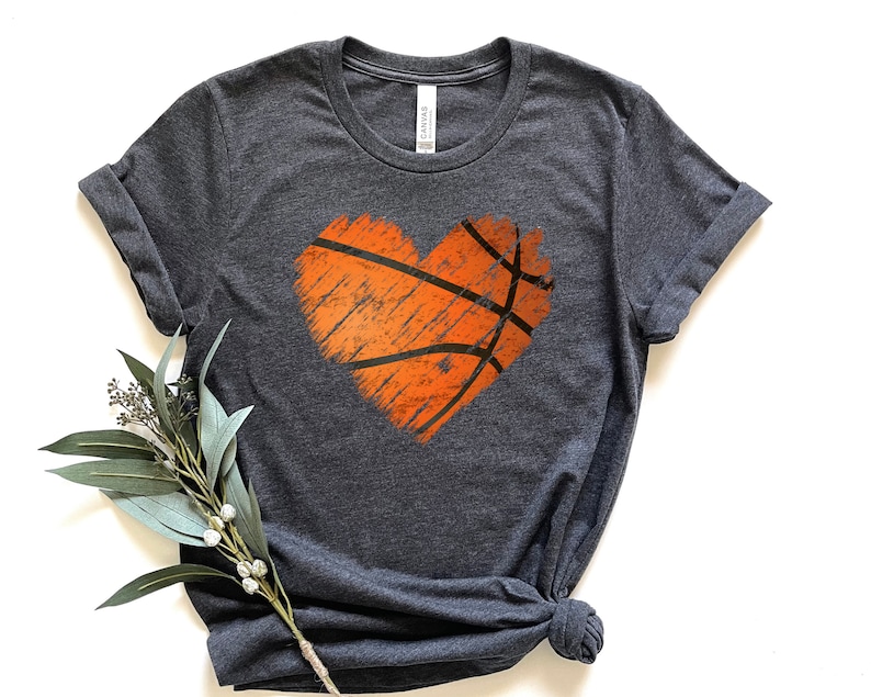 May include: A dark heather grey t-shirt featuring a distressed orange basketball graphic in the shape of a heart.