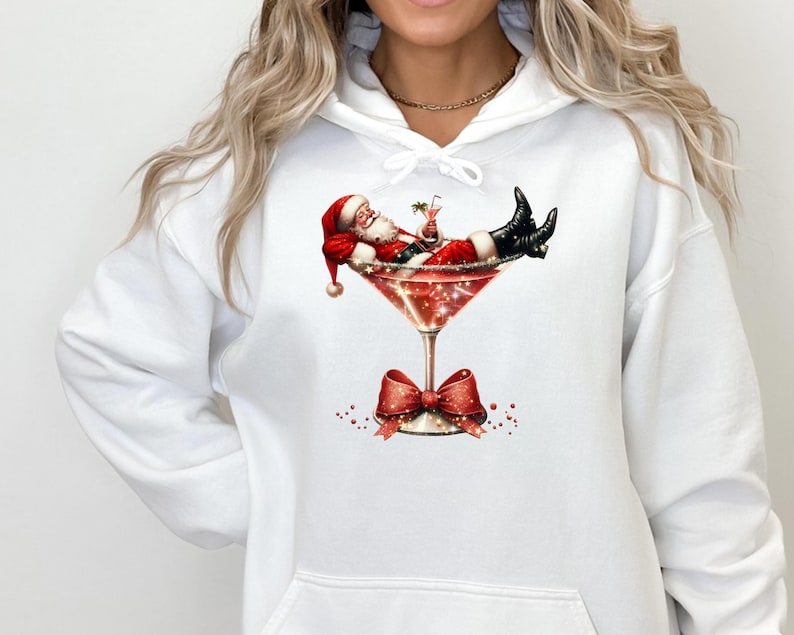 May include: White hooded sweatshirt with a graphic of Santa Claus relaxing in a martini glass with a red bow on the stem.
