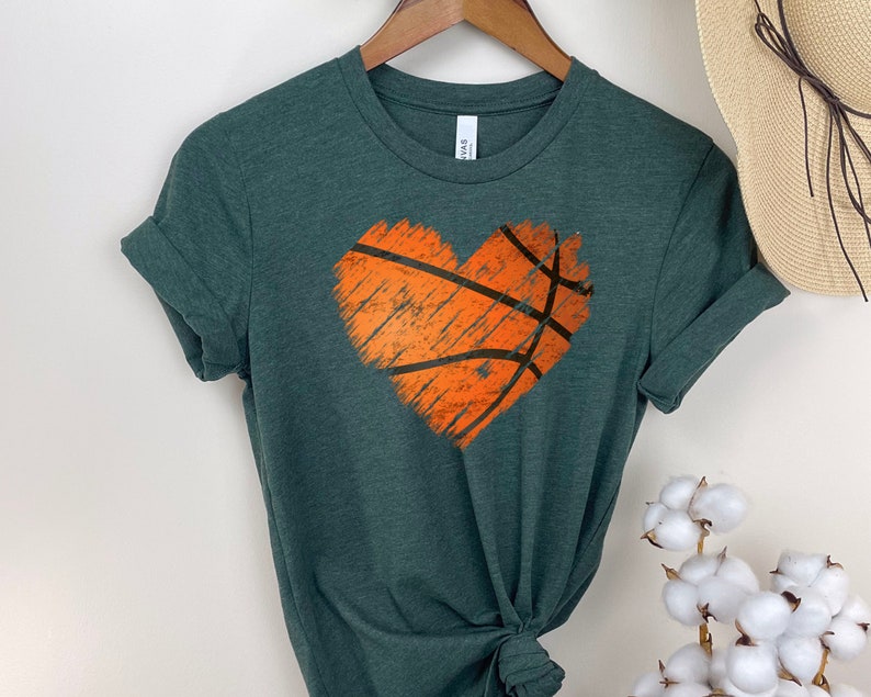 May include: A dark green t-shirt featuring a distressed orange basketball design in the shape of a heart.