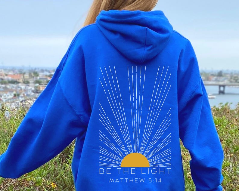 May include: A royal blue hoodie with a white sunburst design and the text "BE THE LIGHT" and "MATTHEW 5:14" in white.