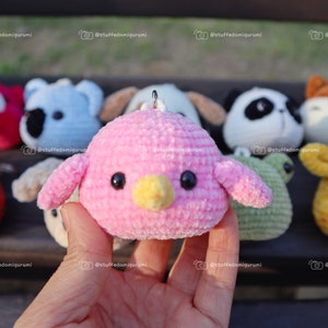 May include: A collection of crocheted animal plushies, including a pink bird, a red tiger, a blue koala, a white panda, a brown dog, a green frog, a yellow giraffe, and a brown fox. The plushies are all small and have cute faces.
