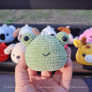 May include: A collection of small crocheted animal plushies, including a koala, dog, frog, panda, giraffe, and pig. The plushies are all green, blue, brown, yellow, and pink.
