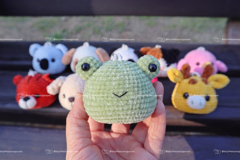 May include: A collection of small crocheted animal plushies, including a koala, dog, frog, panda, giraffe, and pig. The plushies are all green, blue, brown, yellow, and pink.