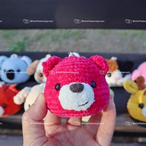 May include: A collection of small crocheted stuffed animals, including a pink bear, a blue koala, a brown dog, a black and white cat, a pink pig, and a yellow giraffe. The animals are all holding a small key chain.