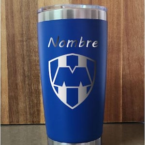 May include: A blue stainless steel tumbler with a white logo and the word "Nombre" on it.