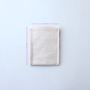 Puede incluir: Una peque&ntilde;a bolsa de lona blanca con un borde rosa. La bolsa mide 7,2 cm de ancho y 10,5 cm de alto.