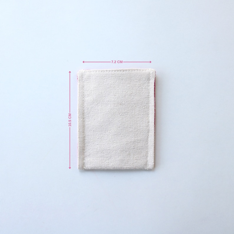 Puede incluir: Una peque&ntilde;a bolsa de lona blanca con un borde rosa. La bolsa mide 7,2 cm de ancho y 10,5 cm de alto.