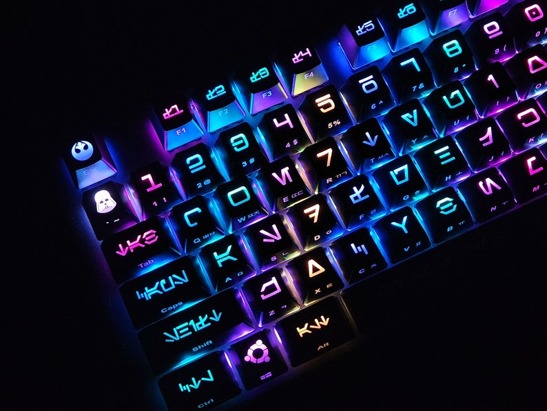 May include: A black keyboard with colorful backlighting. The keys have symbols from the Star Wars universe, including the Death Star, the Millennium Falcon, and the Rebel Alliance logo.