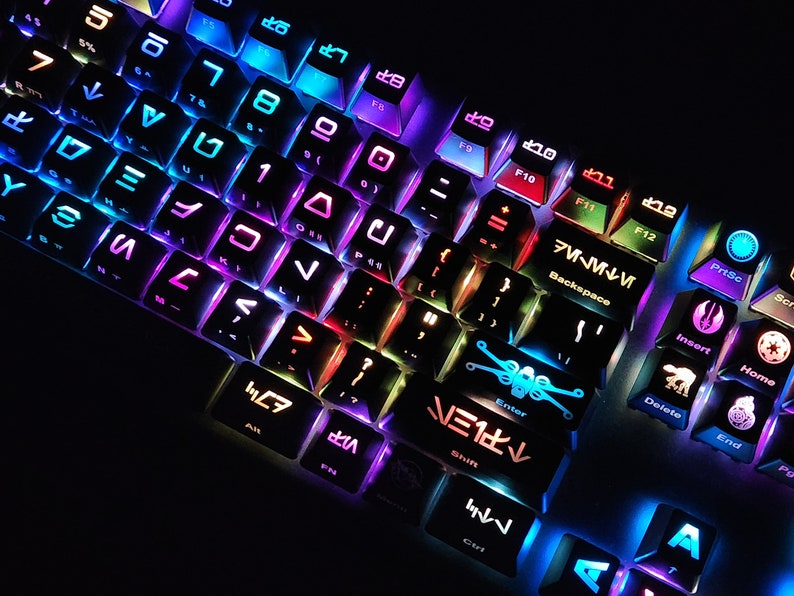 May include: A black keyboard with rainbow colored lights. The keys have Star Wars themed symbols on them, including the Millennium Falcon, X-Wing, and Darth Vader.