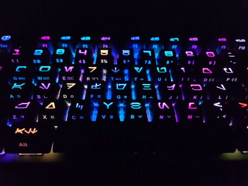 May include: A black keyboard with colorful backlighting. The keys are labeled with letters, numbers, and symbols. The backlighting is in shades of blue, purple, and pink.