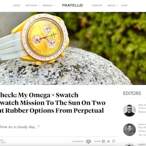 May include: A yellow and white wristwatch with a yellow face and white band. The watch is set on a gray stone. The watch has three smaller dials and a white bezel. The watch is a MoonSwatch Mission To The Sun.