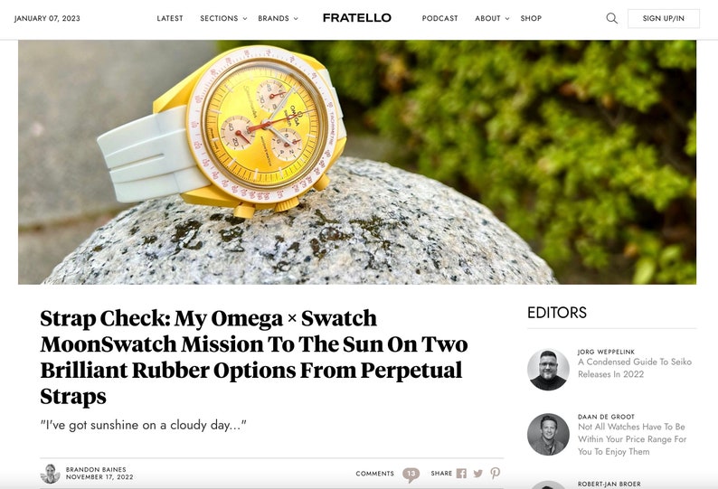 May include: A yellow and white wristwatch with a yellow face and white band. The watch is set on a gray stone. The watch has three smaller dials and a white bezel. The watch is a MoonSwatch Mission To The Sun.