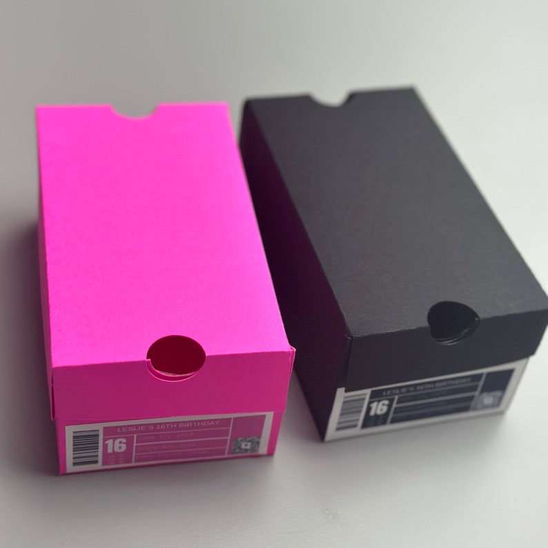 May include: Two shoe boxes, one pink and one black. The pink box has the text "LESLIE'S 16TH BIRTHDAY" and the number "16" on it. The black box has the number "16" on it.