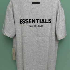 Fear Of God Essentials Tシャツ – ライトオートミールベージュTシャツ – オーバーサイズストリートウェア サイズL – ミニマリストユニセックスデザイナーシャツ