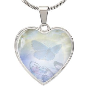 May include: A silver heart-shaped pendant necklace with a clear glass insert featuring a blue butterfly against a white background. The butterfly is surrounded by other butterflies in the background.