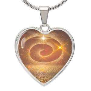 Puede incluir: Un collar de corazón plateado con un diseño de espiral dorado sobre un fondo brillante. La espiral está rodeada por un brillo dorado.
