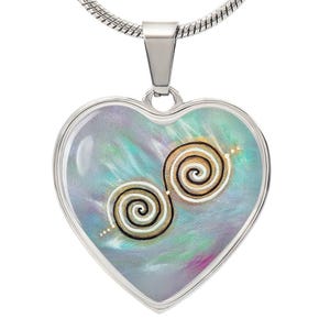 Puede incluir: Un collar con un colgante en forma de corazón plateado, sobre un fondo azul y verde, con dos diseños en espiral dorados.