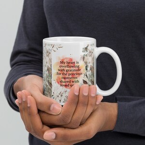 May include: White ceramic mug with a floral design and the text "My heart is overflowing with gratitude for the precious moments shared with loved ones".