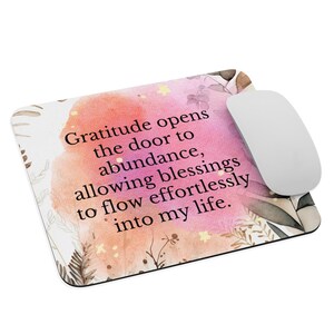 Puede incluir: Una alfombrilla de ratón de acuarela rosa y naranja con una cita que dice "La gratitud abre la puerta a la abundancia, permitiendo que las bendiciones fluyan sin esfuerzo en mi vida."