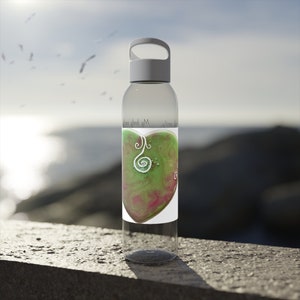 May include: A clear reusable water bottle with a white lid and a handle. The bottle has a label with a green and pink heart design and the text "My body, my temple".