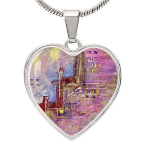 Peut inclure: Un collier avec un pendentif en forme de cœur argenté orné d'une peinture abstraite aux couleurs rose, violet, bleu, or et rouge.