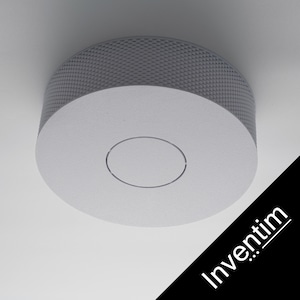 Peut inclure: Un dispositif circulaire moderne monté au plafond, avec une partie supérieure grise texturée et une base blanche lisse. Une fine rainure circulaire est gravée dans la surface blanche. Le mot "Inventim" est imprimé sur une bande diagonale noire.